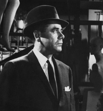 A man dressed in a suit surrounded by mannequins